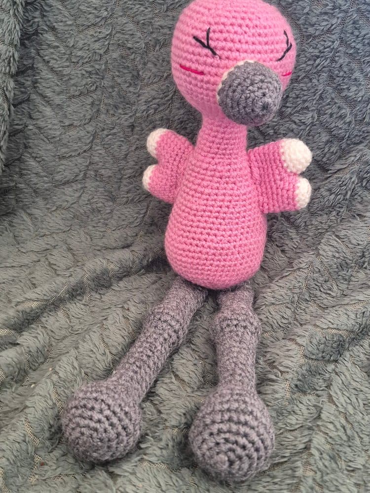 Photo de téléphone d'origine d'une créatrice : doudou flamant rose au crochet sur un plaid gris